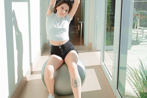 Athletic person stretching in a modern room with large windows and soft light.